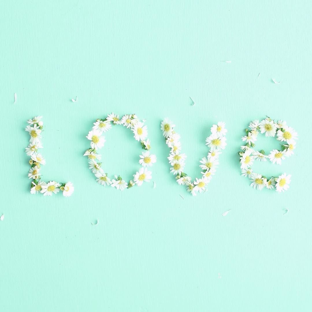 The word love spelled out with flowers on a blue background - Mint green