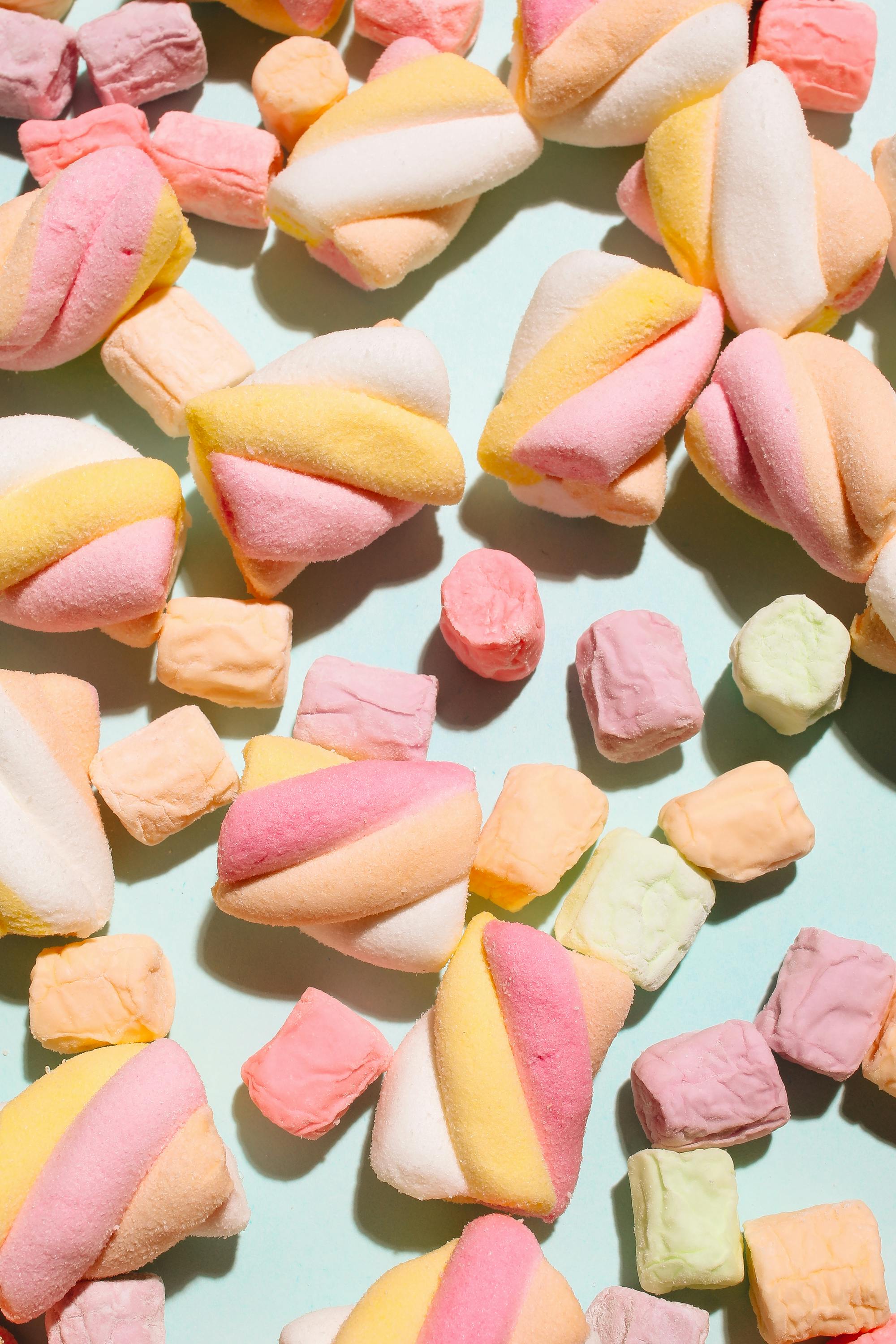 A close up of colorful marshmallows on a blue background - Marshmallows