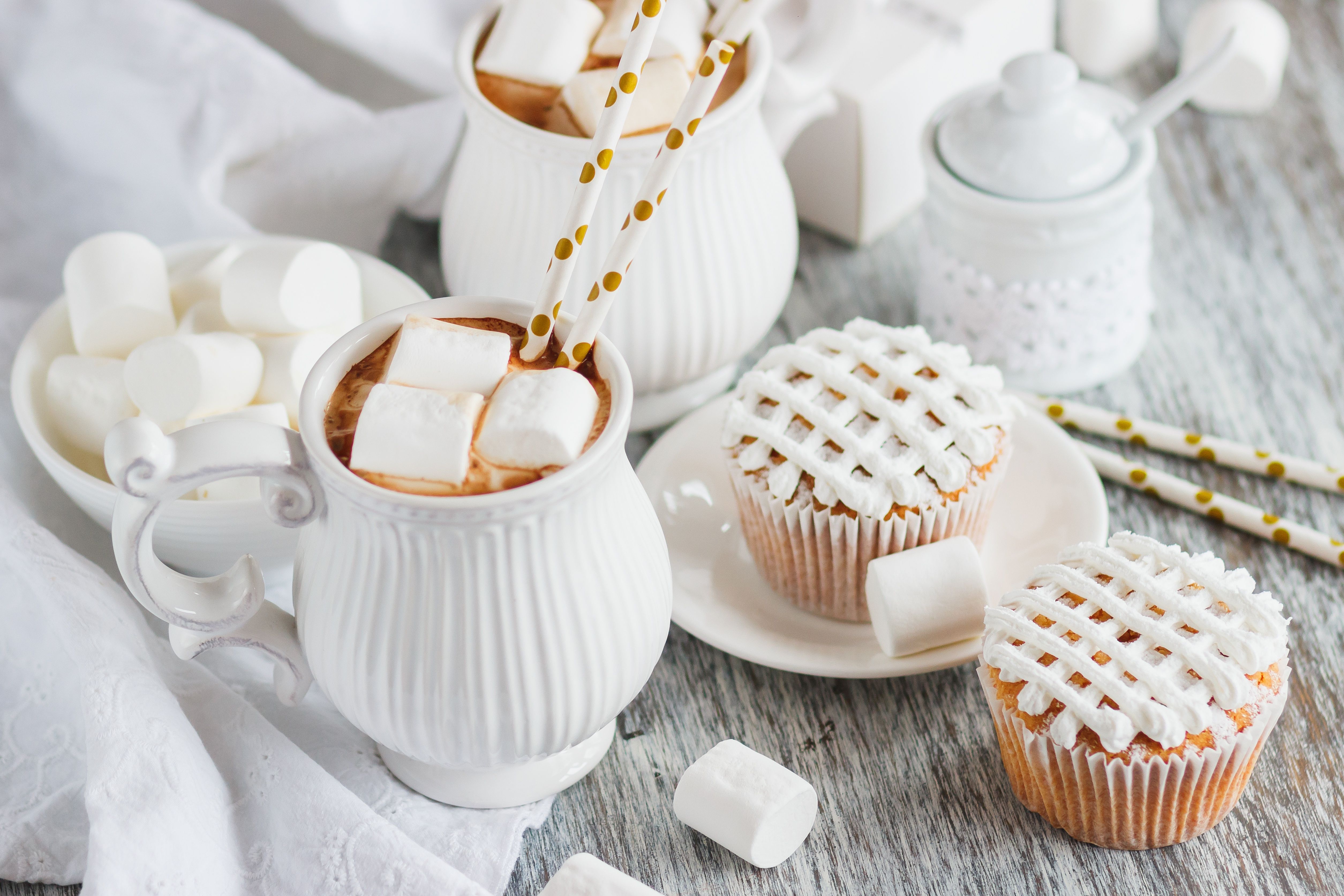 A cup of hot chocolate with marshmallows and two cupcakes - Marshmallows
