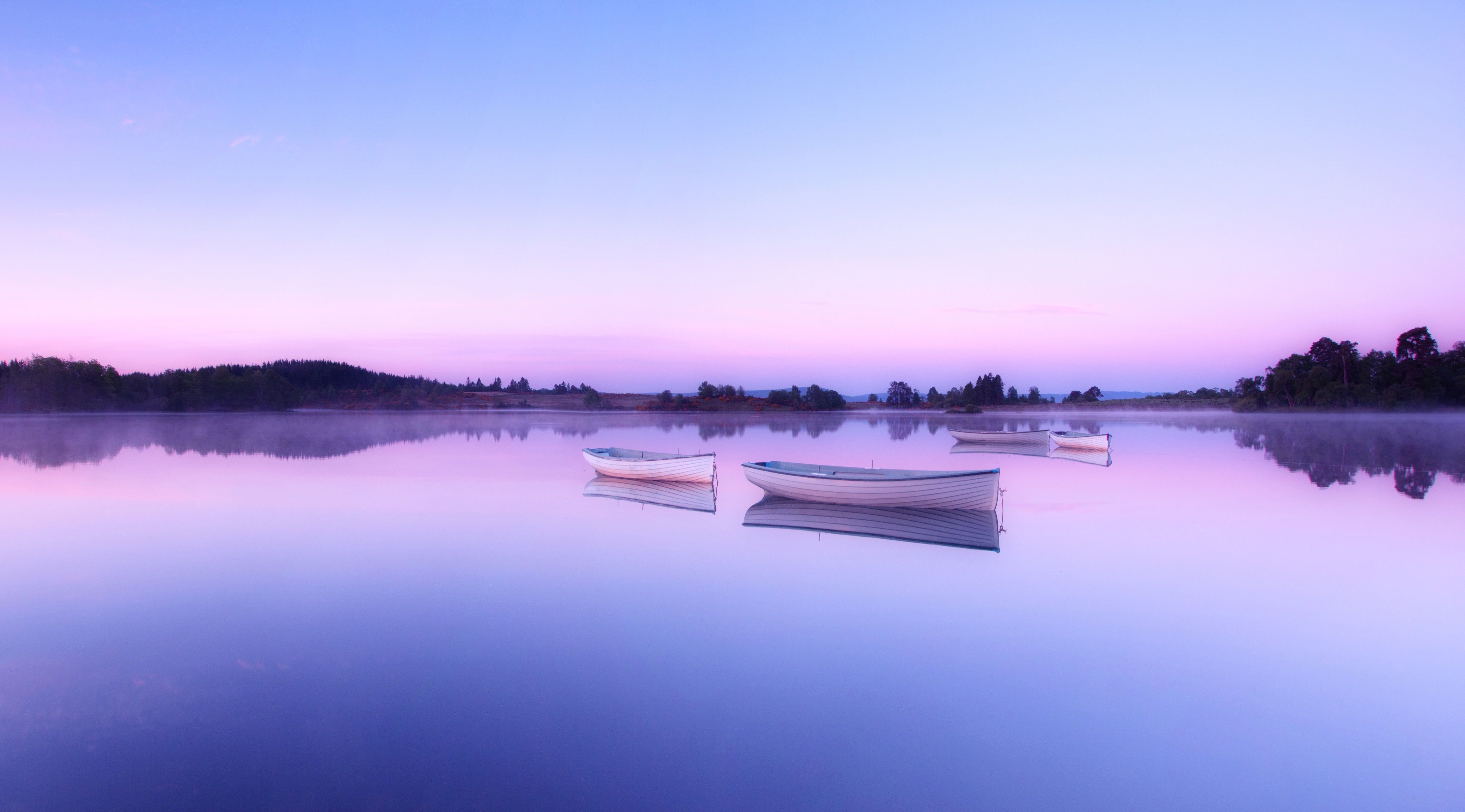 A purple and blue sunset over a lake with three small boats. - Lake