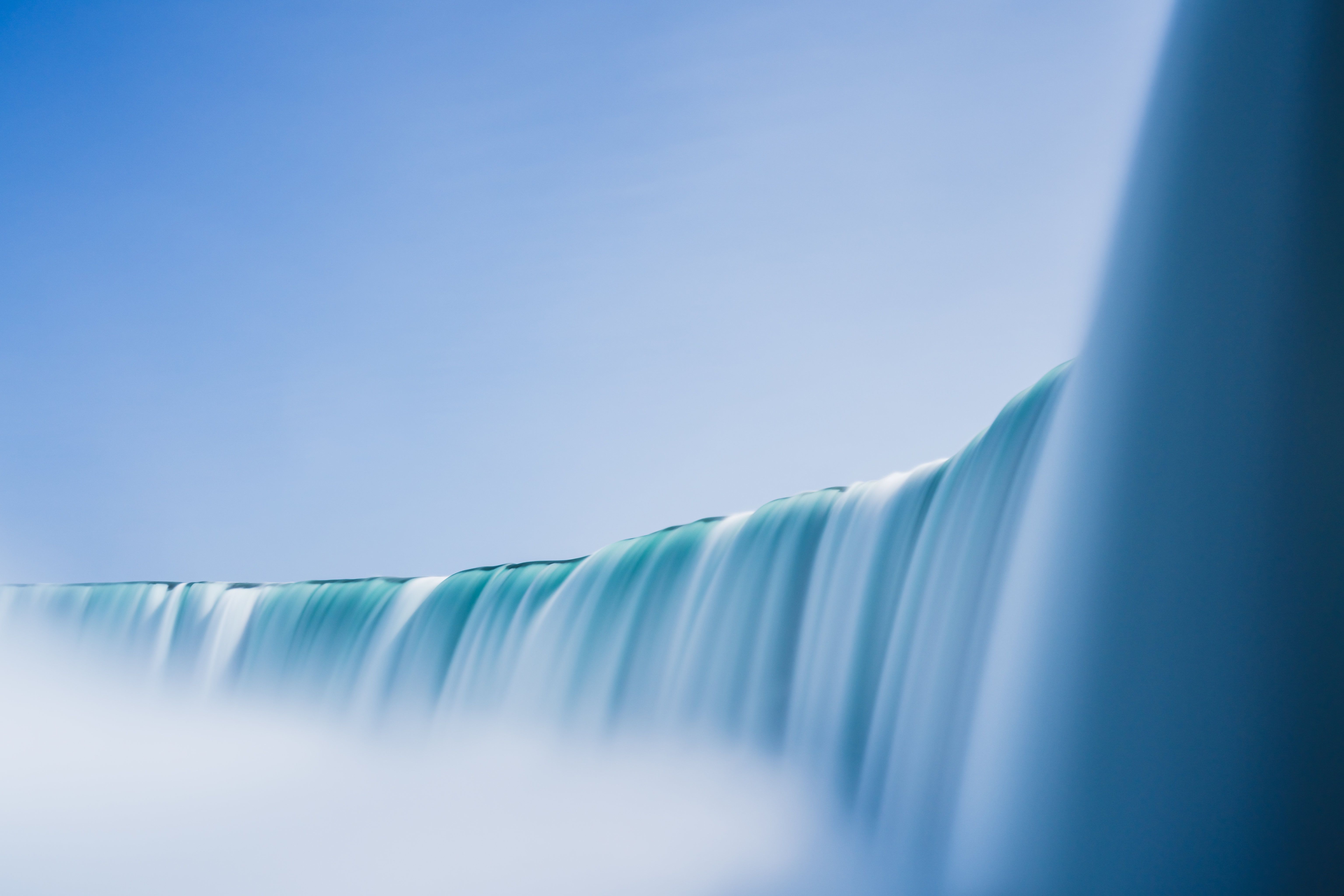 A close up of a waterfall with a blue sky in the background. - Waterfall