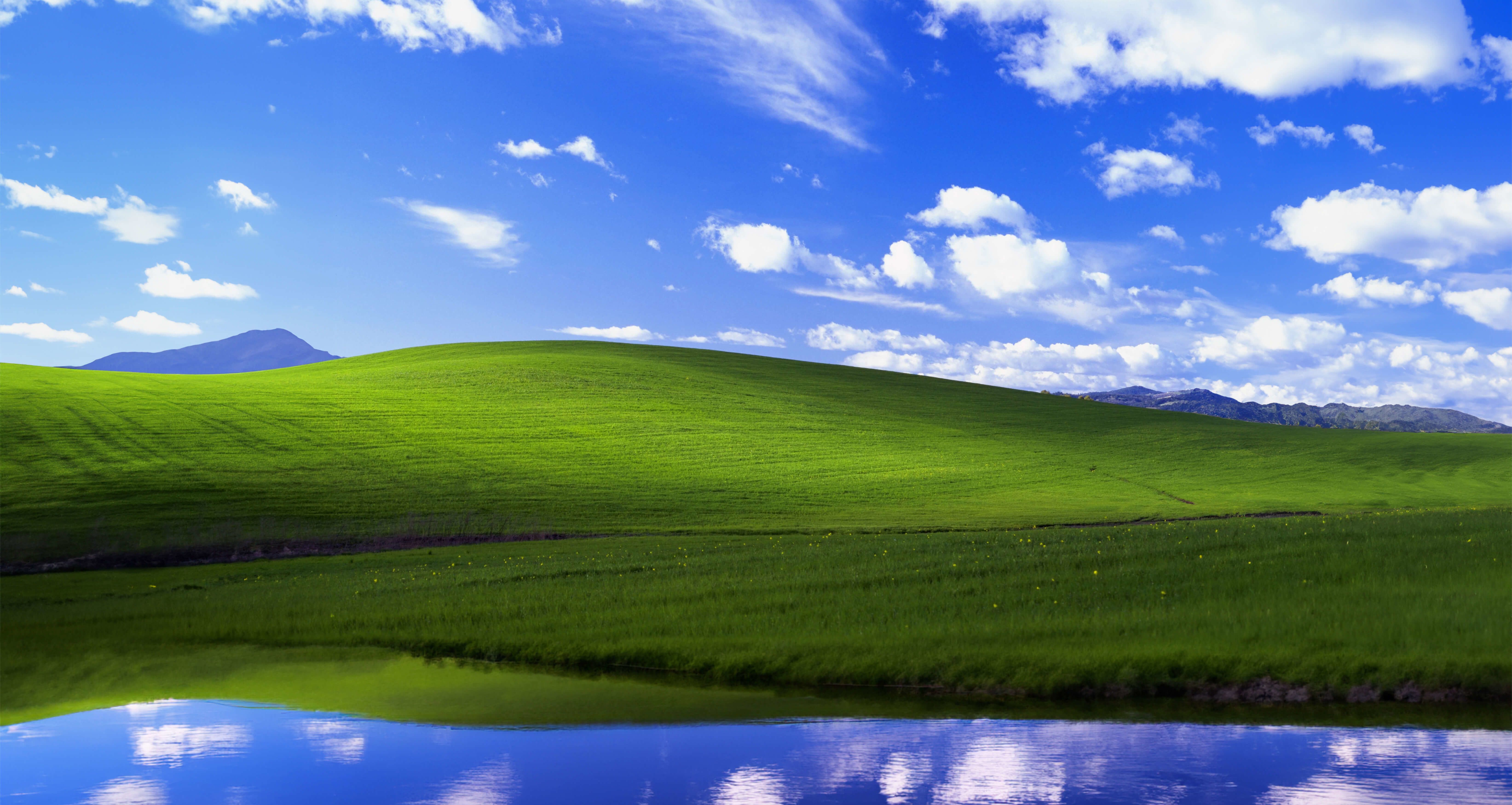A beautiful landscape of a green field with a blue sky and clouds. - Windows 11