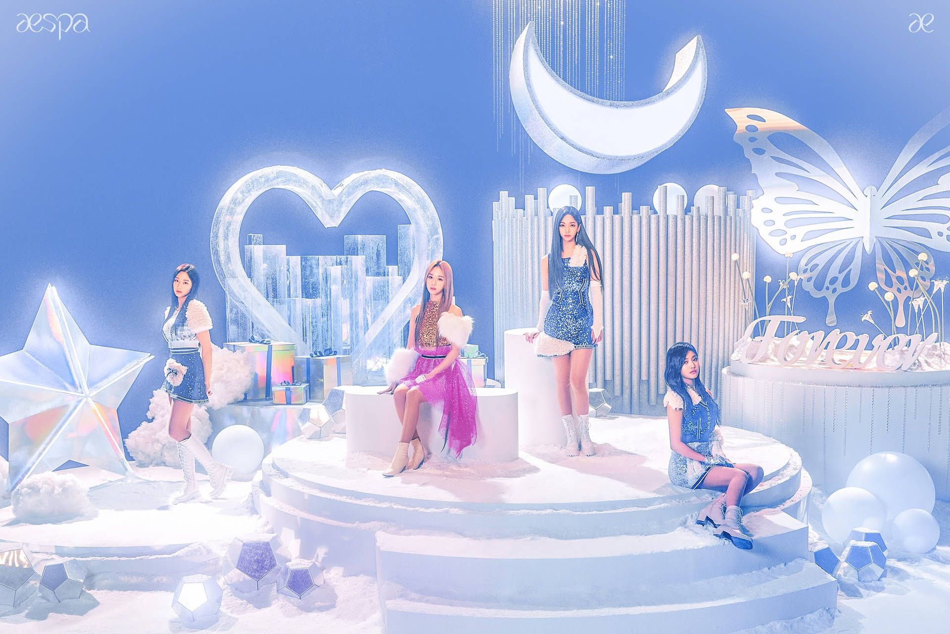 A music video still of four women in a blue room with a white heart, moon, and star. - Aespa