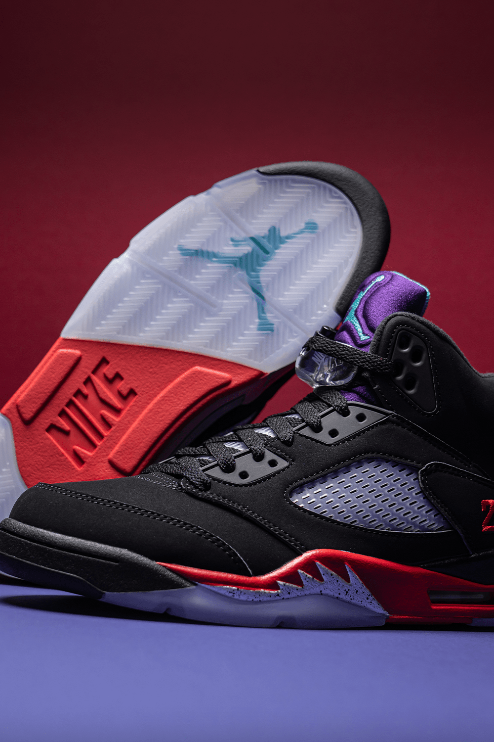 A pair of black and red Nike Air Jordan 5 sneakers on a purple background - Air Jordan 5