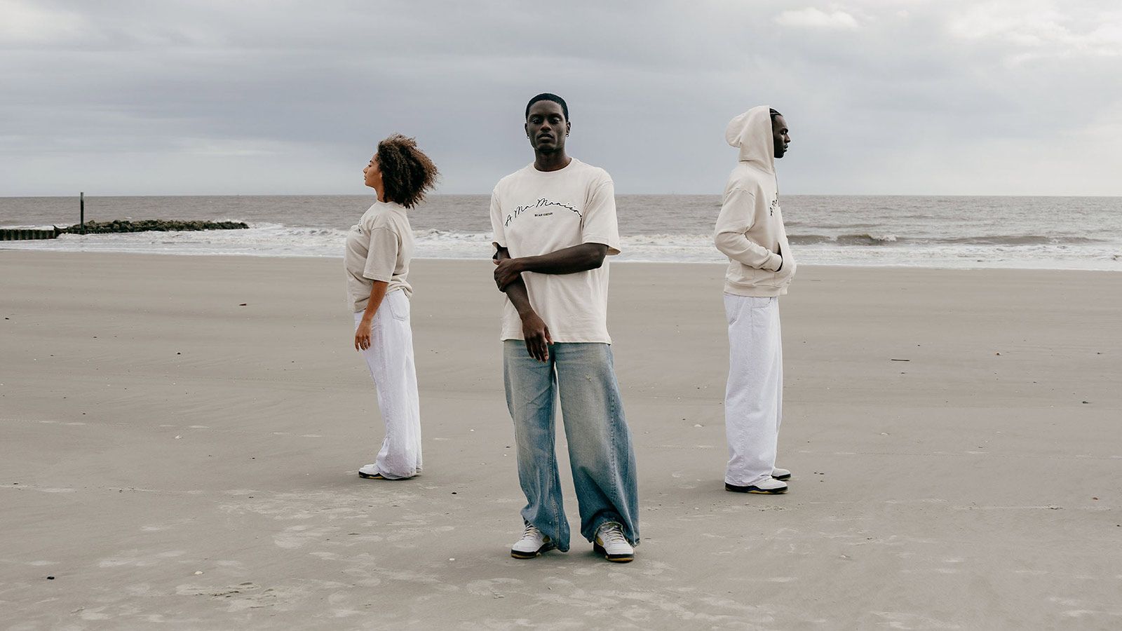 Three people standing on a beach wearing clothes from the collection. - Air Jordan 5