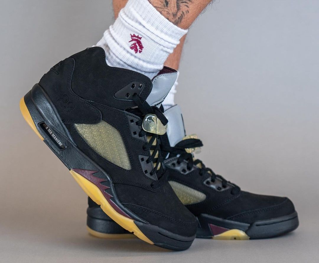 A man wearing black and yellow Nike sneakers. - Air Jordan 5