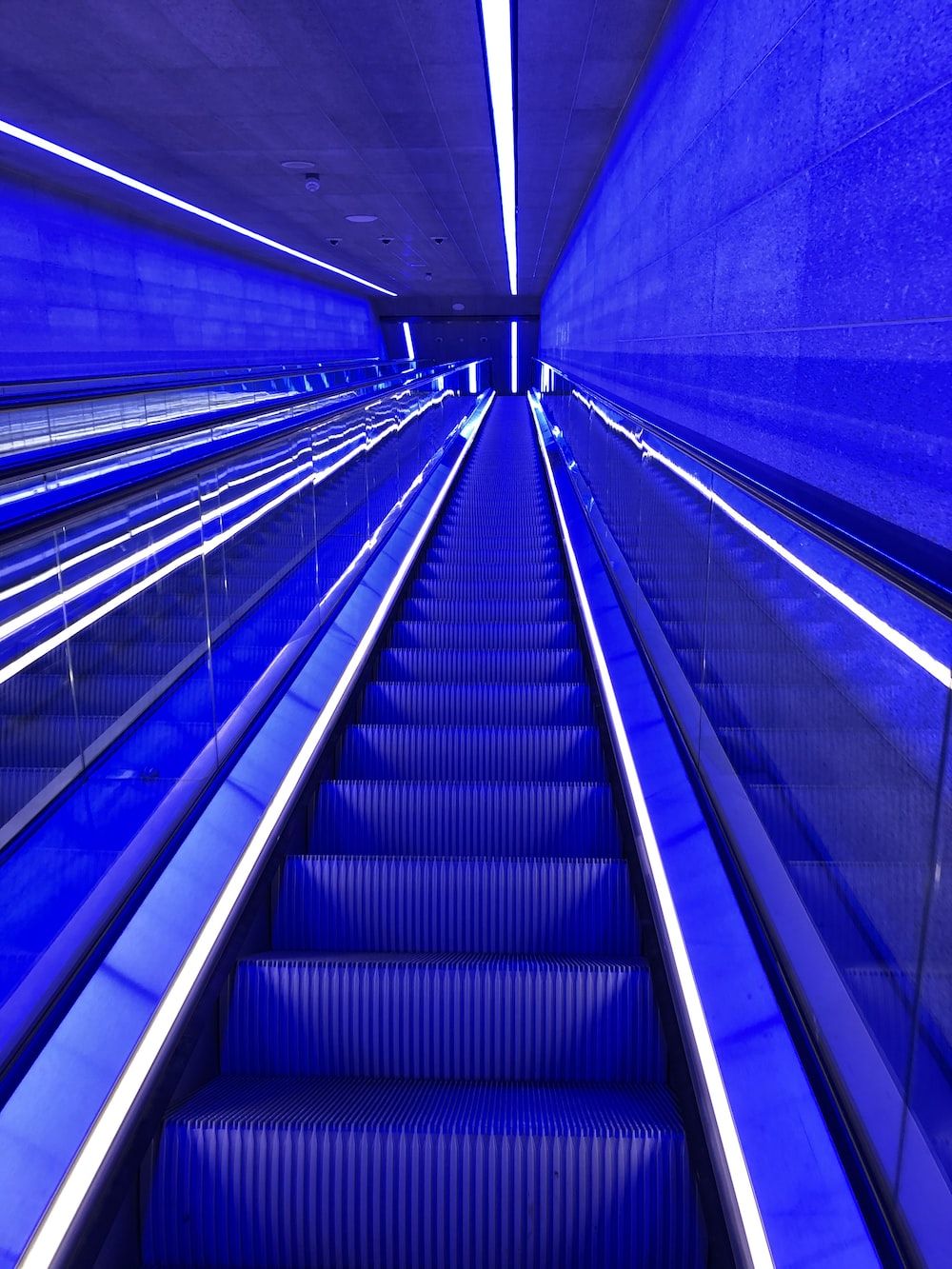 Blue and white escalator in a building - Neon blue