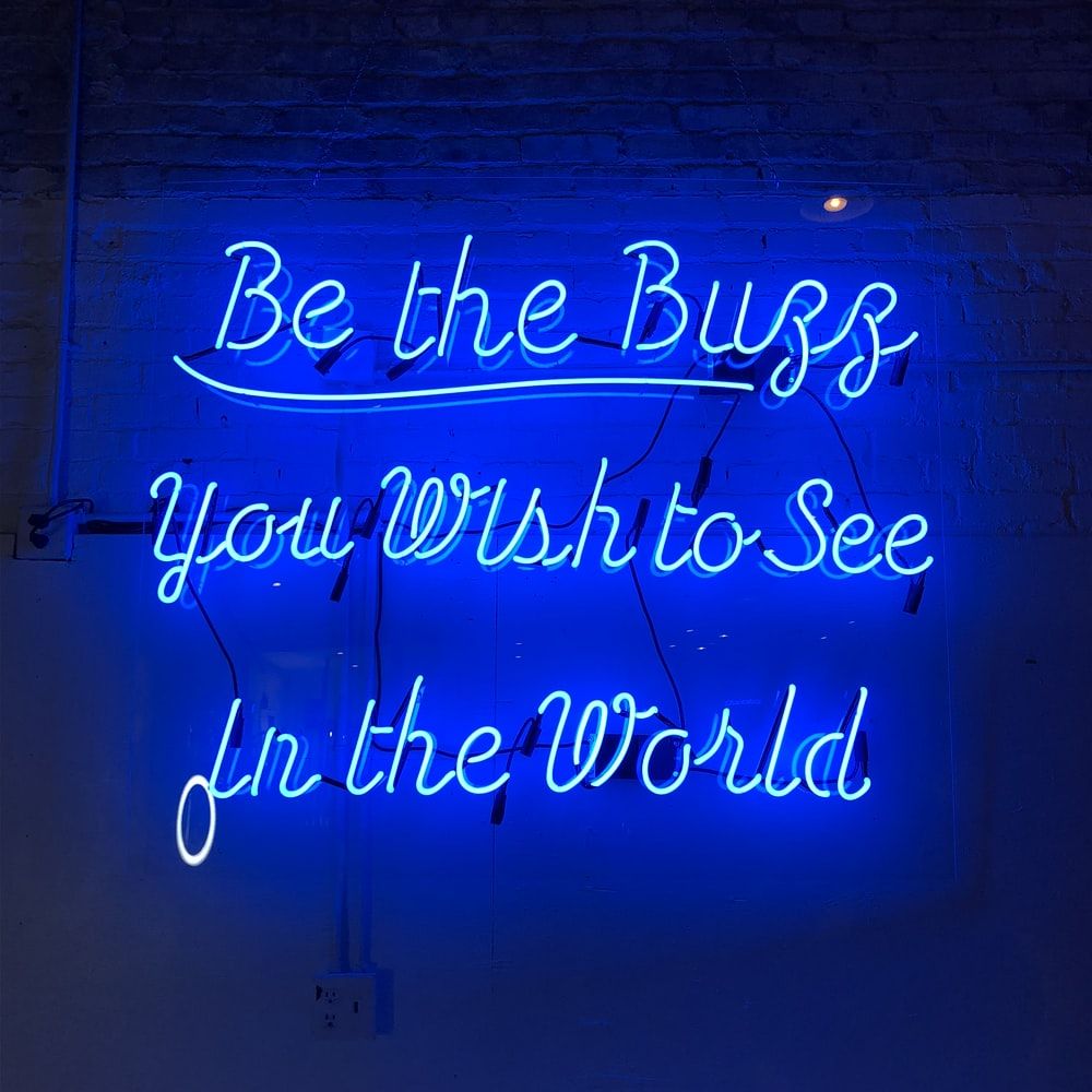A neon sign that says be the bugs you wish to see in this world - Neon blue