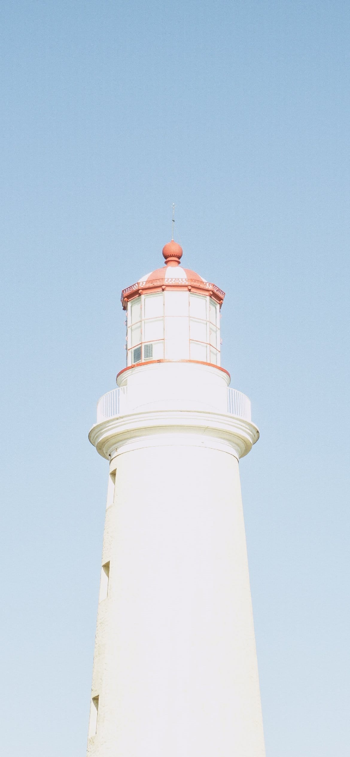 A lighthouse with red and white stripes on it - Light blue