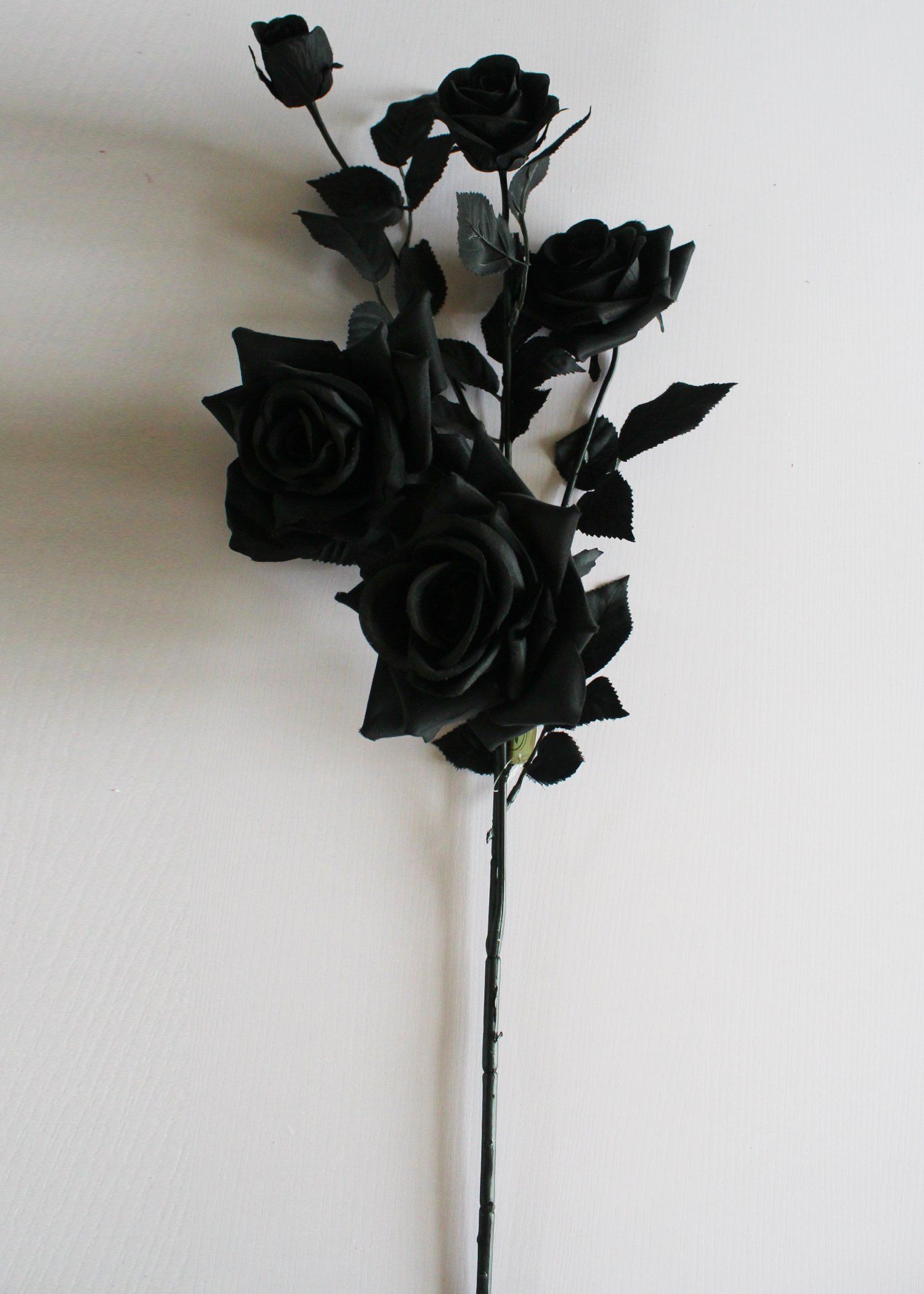 A black flower arrangement on top of white wall - Black rose