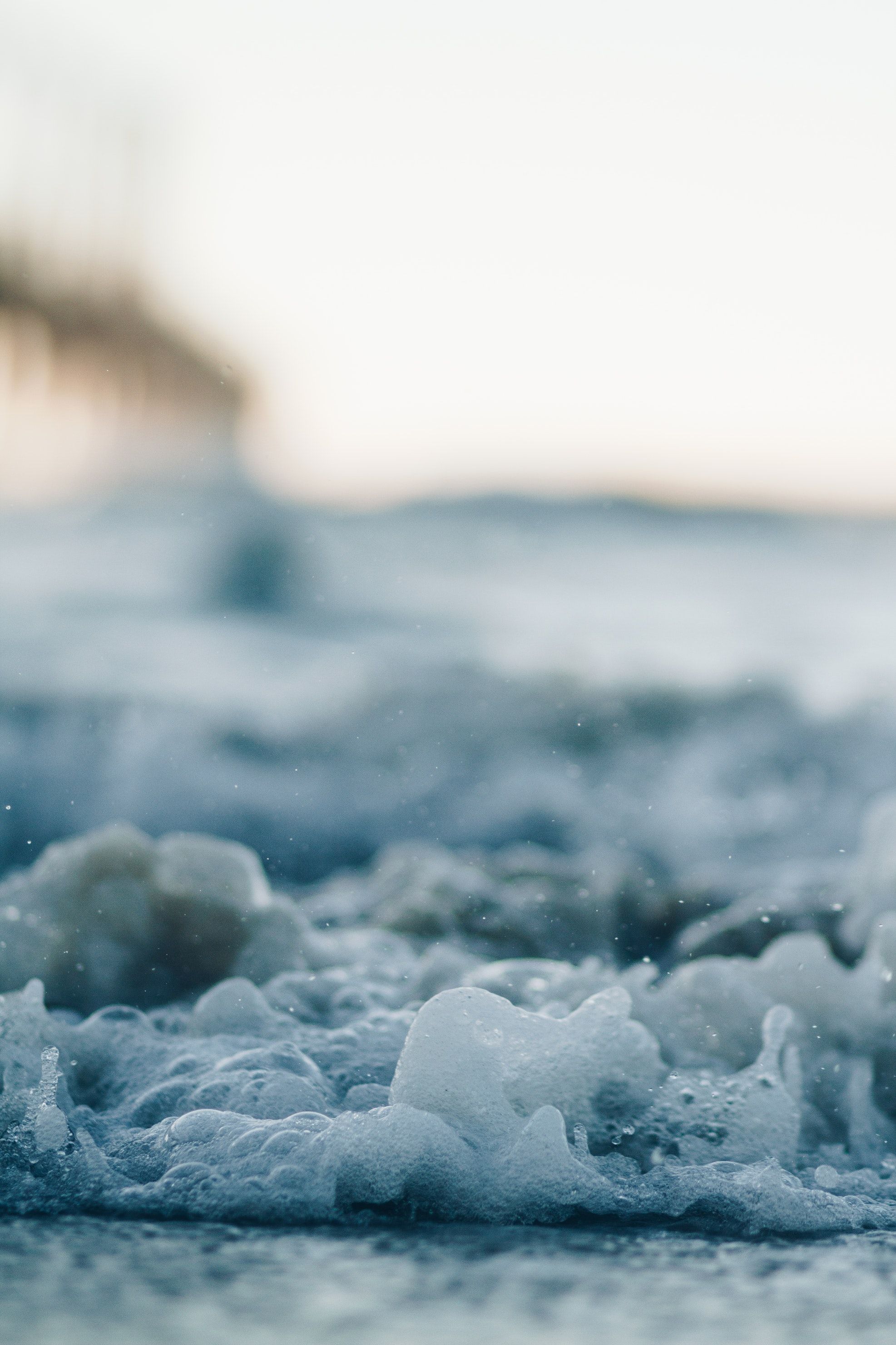 A close up of the water and foam on the shore of a beach - Beach