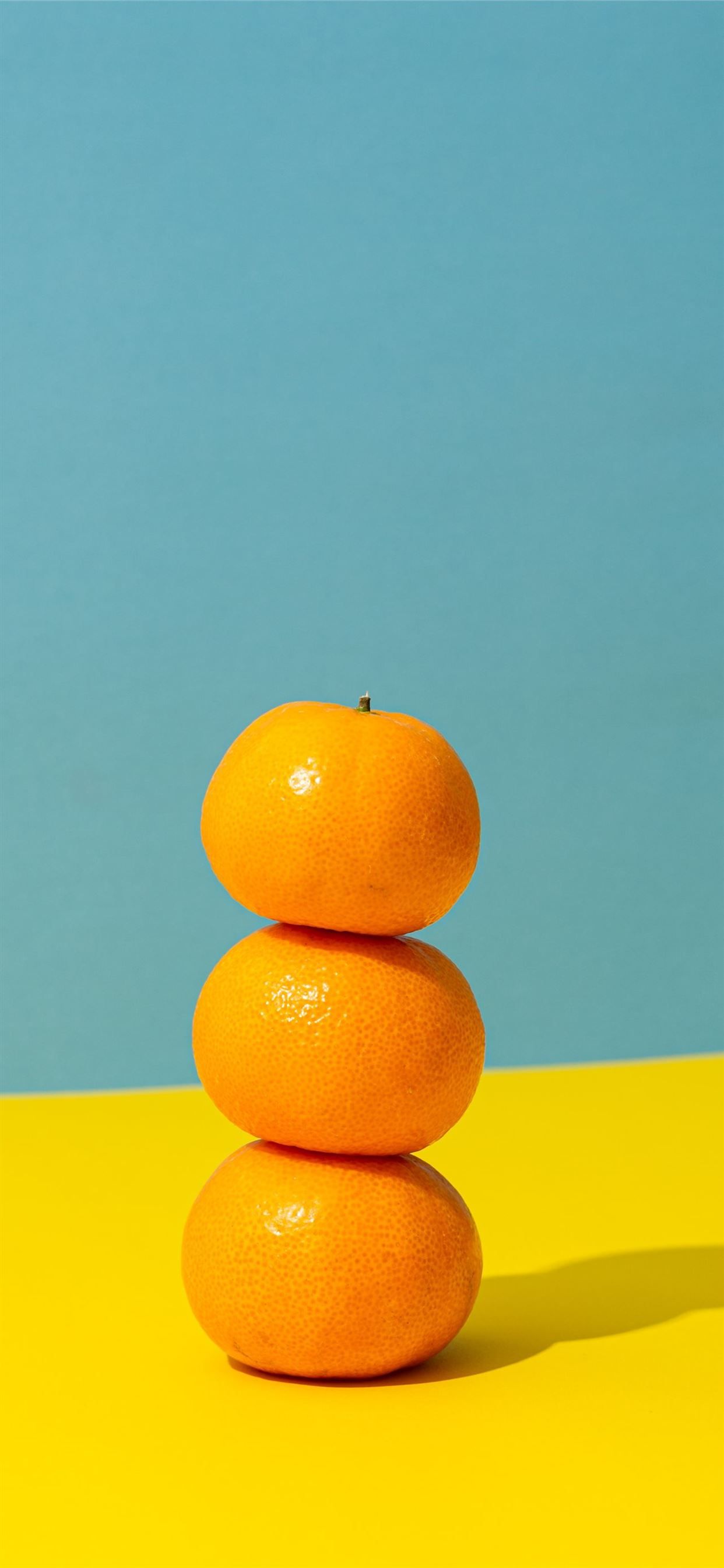 Three oranges stacked on top of each other on a yellow and blue background - Orange, fruit