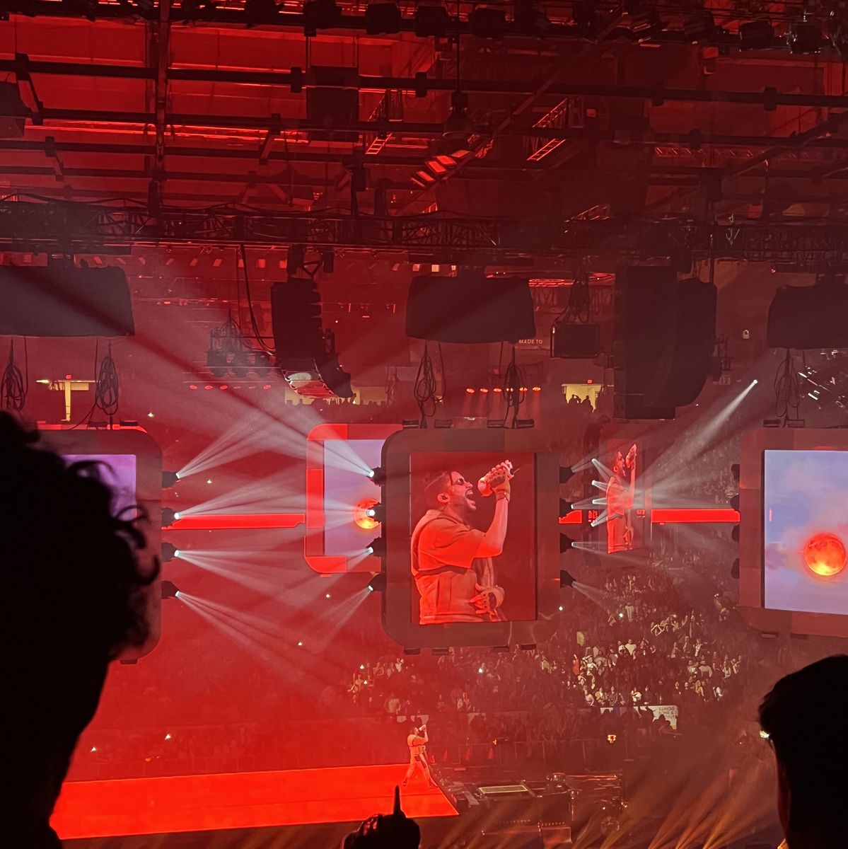 Travis Scott performs on stage with red lights and a red background - Bad Bunny