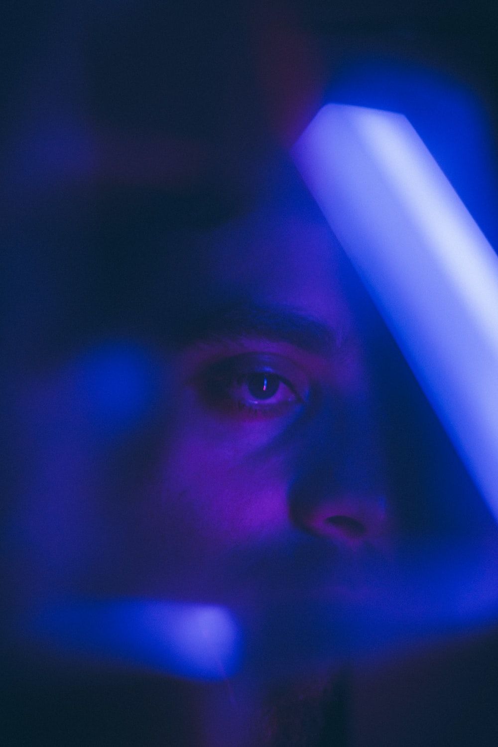 A man with a blue light in front of his face - Dark blue