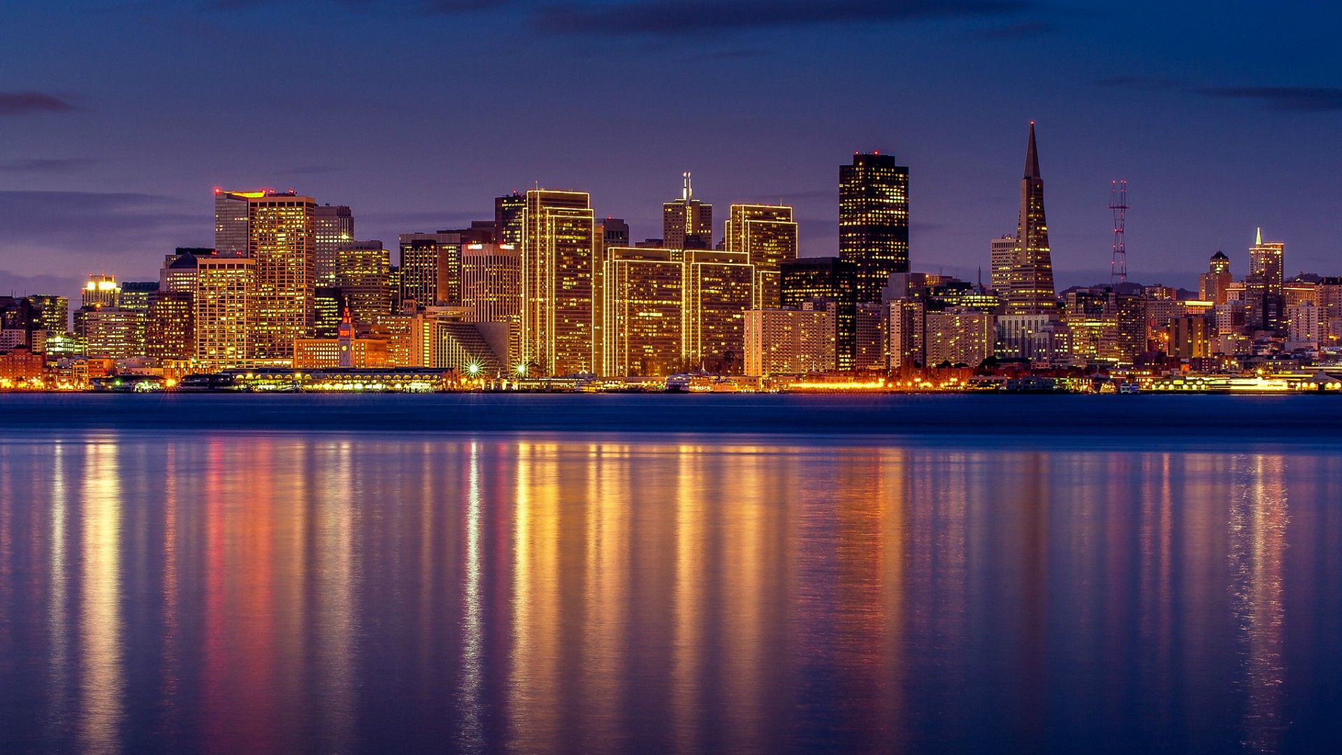 San Francisco at night, with the lights reflecting off the water. - City, California