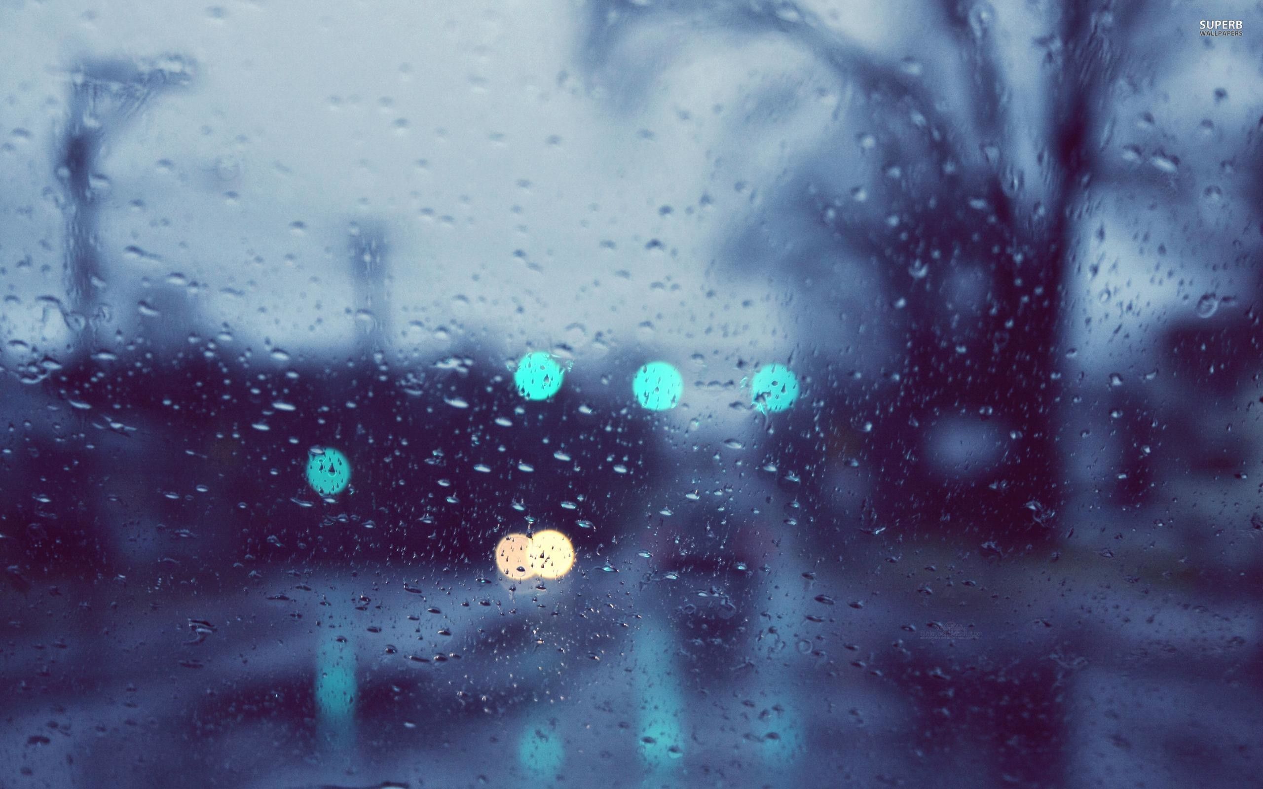 A rain covered window with street lights in the background - Rain