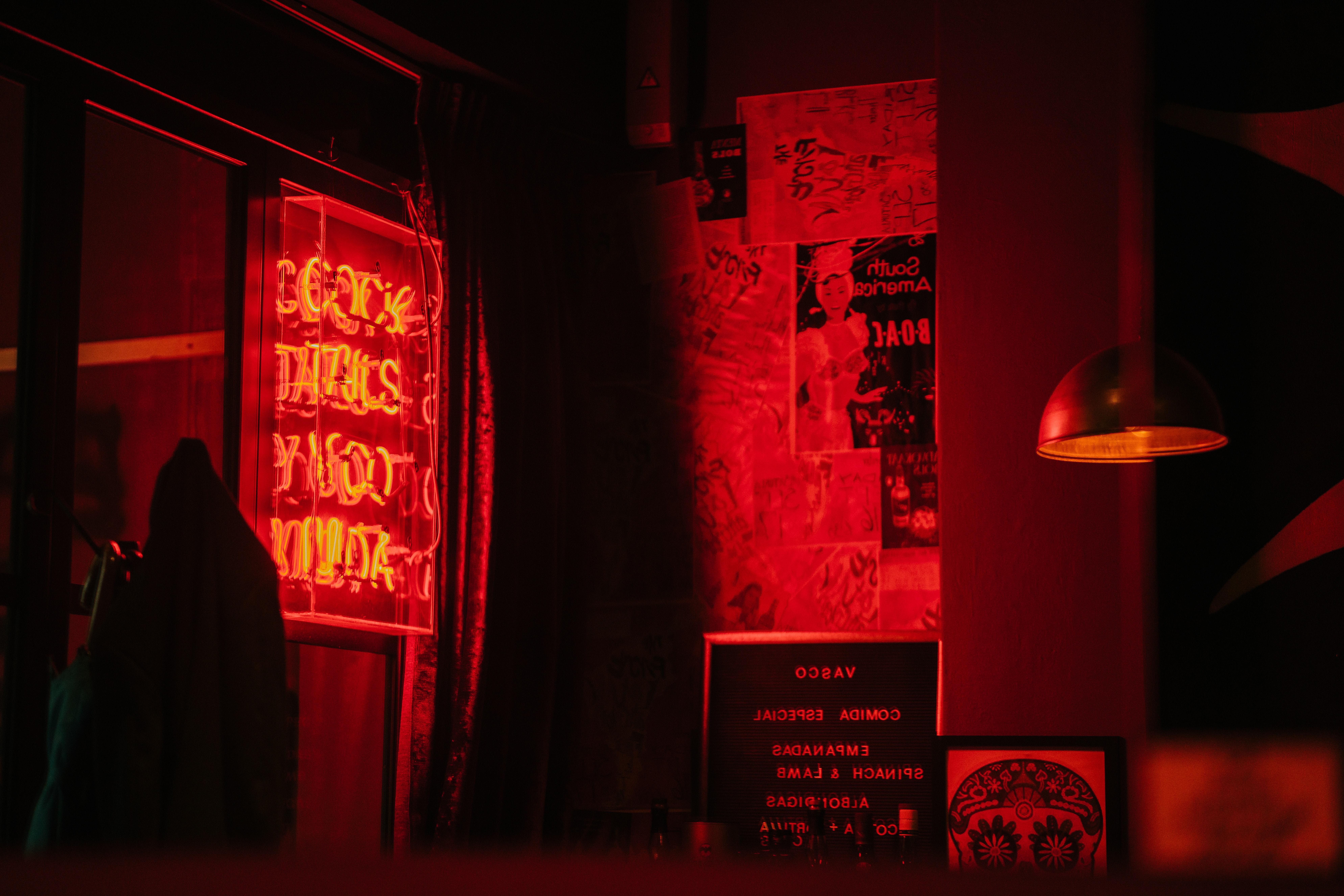 A red neon sign is lit up in a dark room. - Dark red, neon red