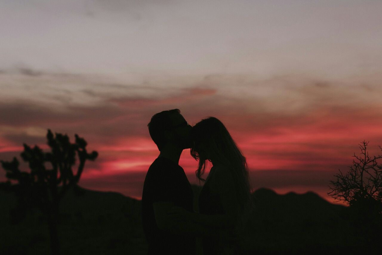 Silhouette of a couple kissing against a sunset - Love