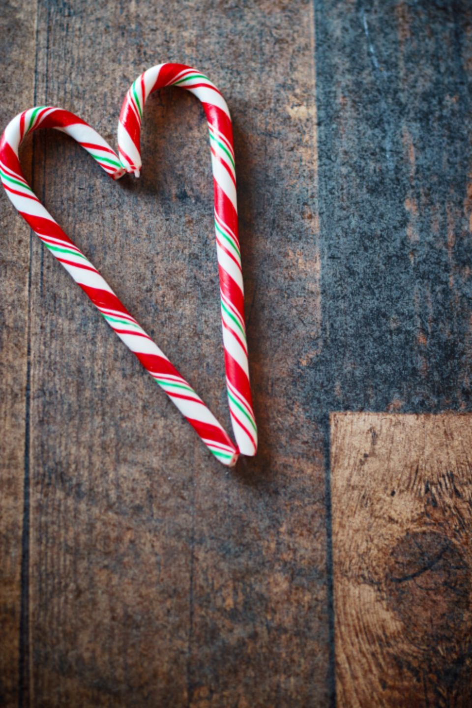 A candy cane heart on a wooden table. - Candy cane