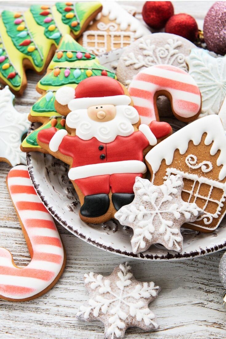 A plate of decorated Christmas cookies including a gingerbread man, candy cane, and Christmas tree. - Candy cane