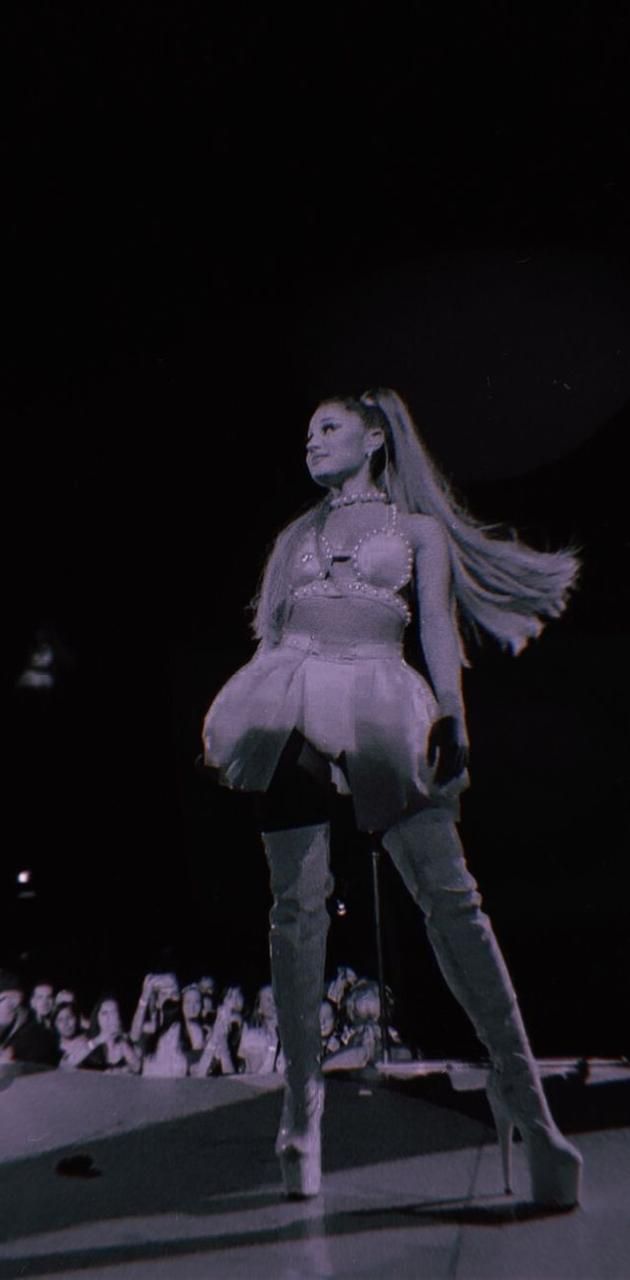 A woman in white boots standing on stage - Ariana Grande