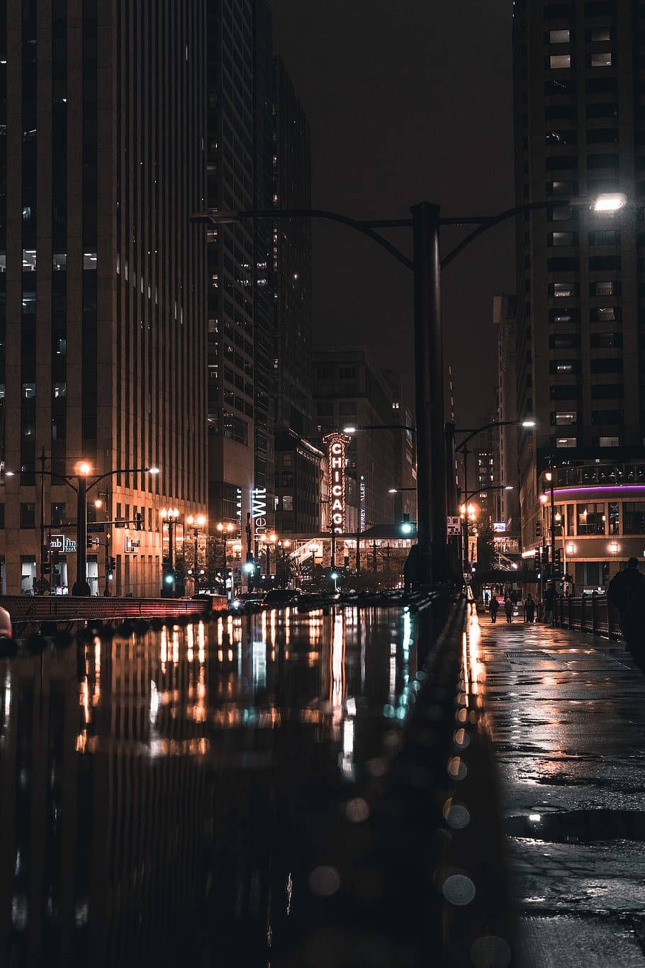A city street at night with cars parked on the side - Chicago, rain