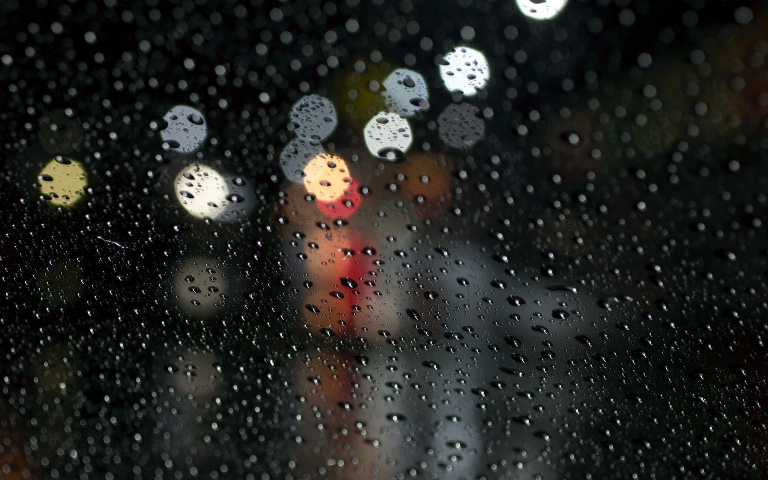 Raindrops on a window with blurred lights in the background - Rain