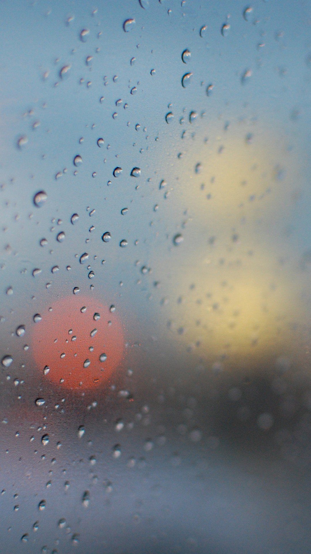 IPhone wallpaper of raindrops on a window with a blurred background of a street - Rain