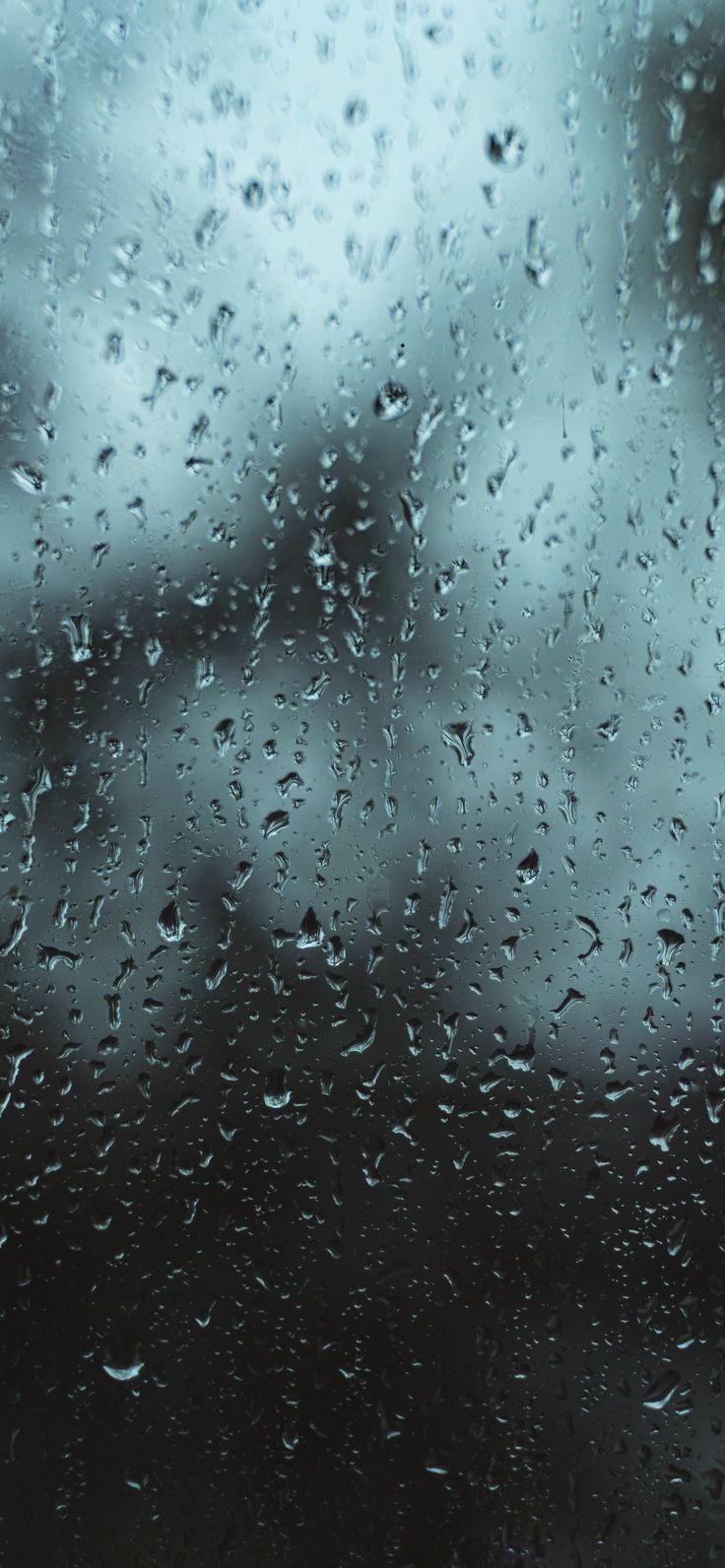 Raindrops on a window with a dark sky in the background - Rain