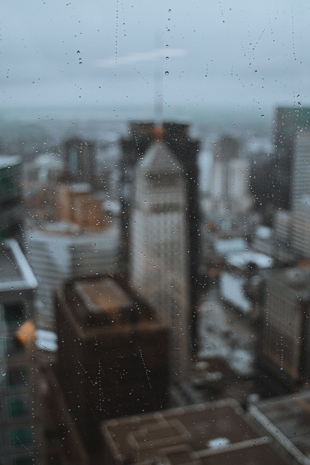 A cityscape is seen through a rain-streaked window. - Rain